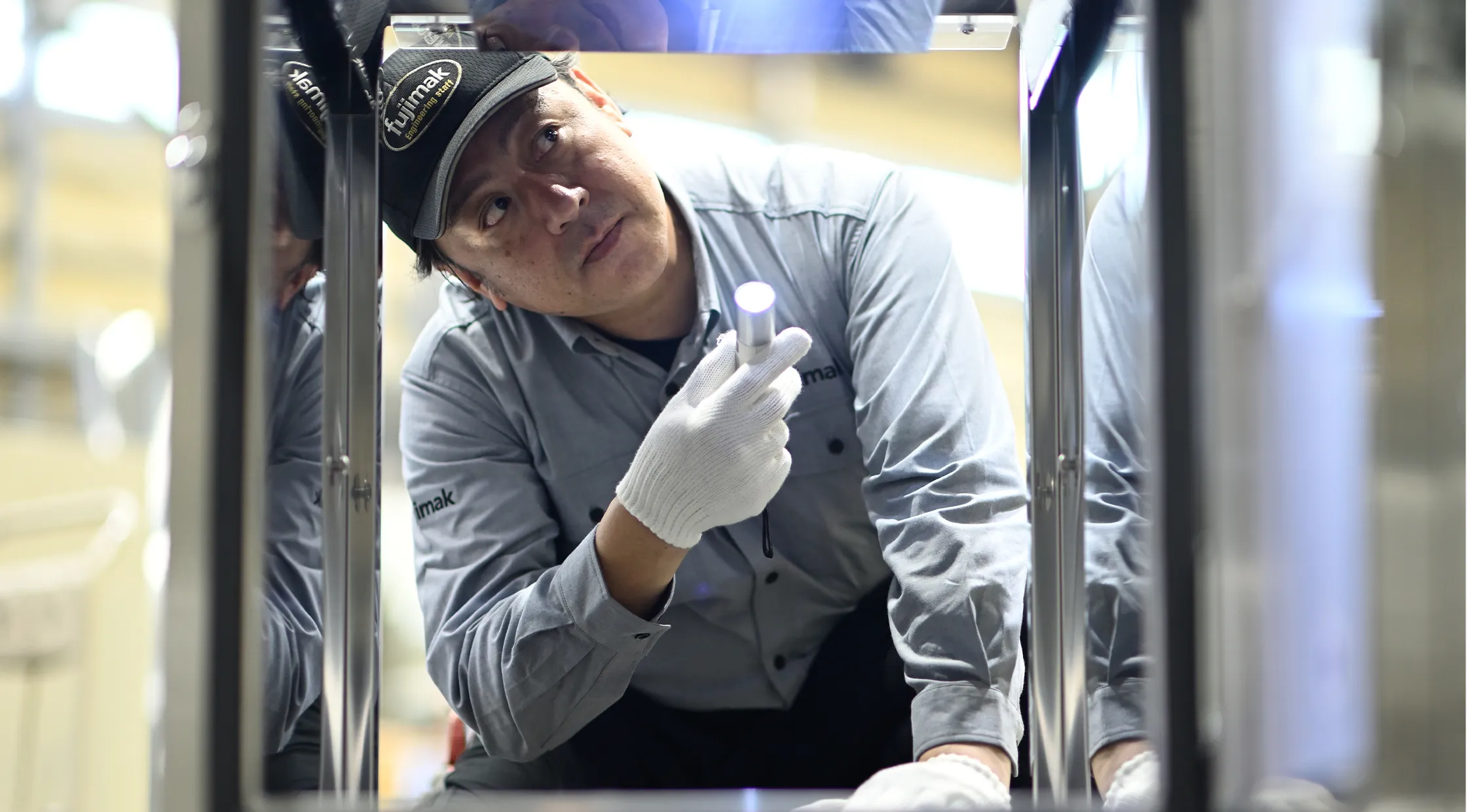 fujimakで働く製品検査職のYさんが機器の下を覗き込んで点検している様子