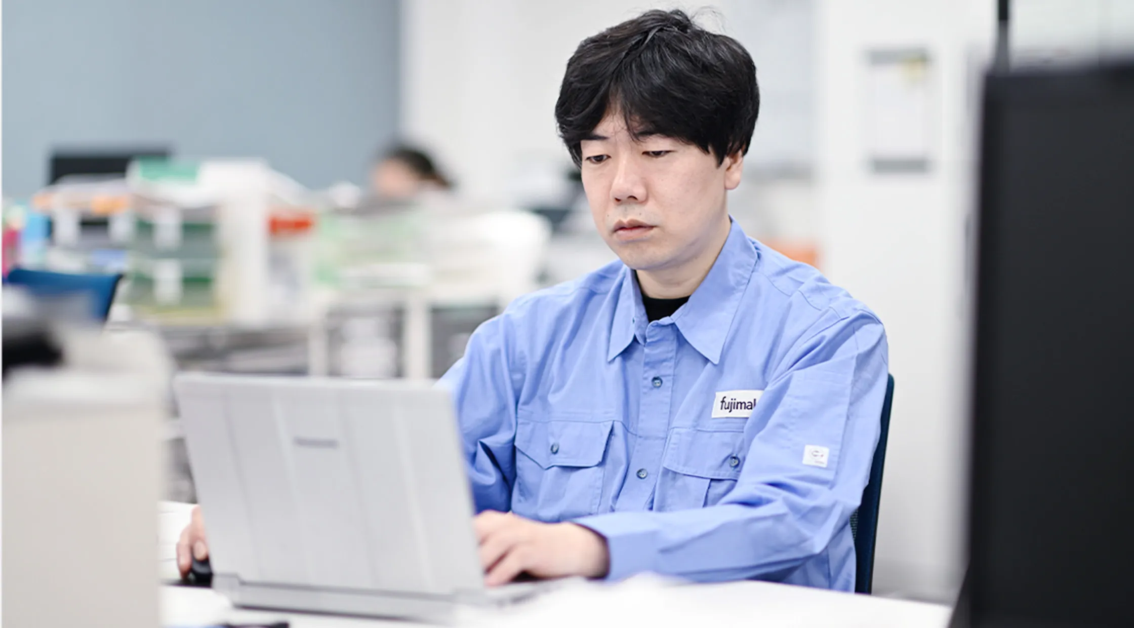 fujimakで働くサービスエンジニア職Kさんがパソコンでお客様とコミュニケーションを取る様子