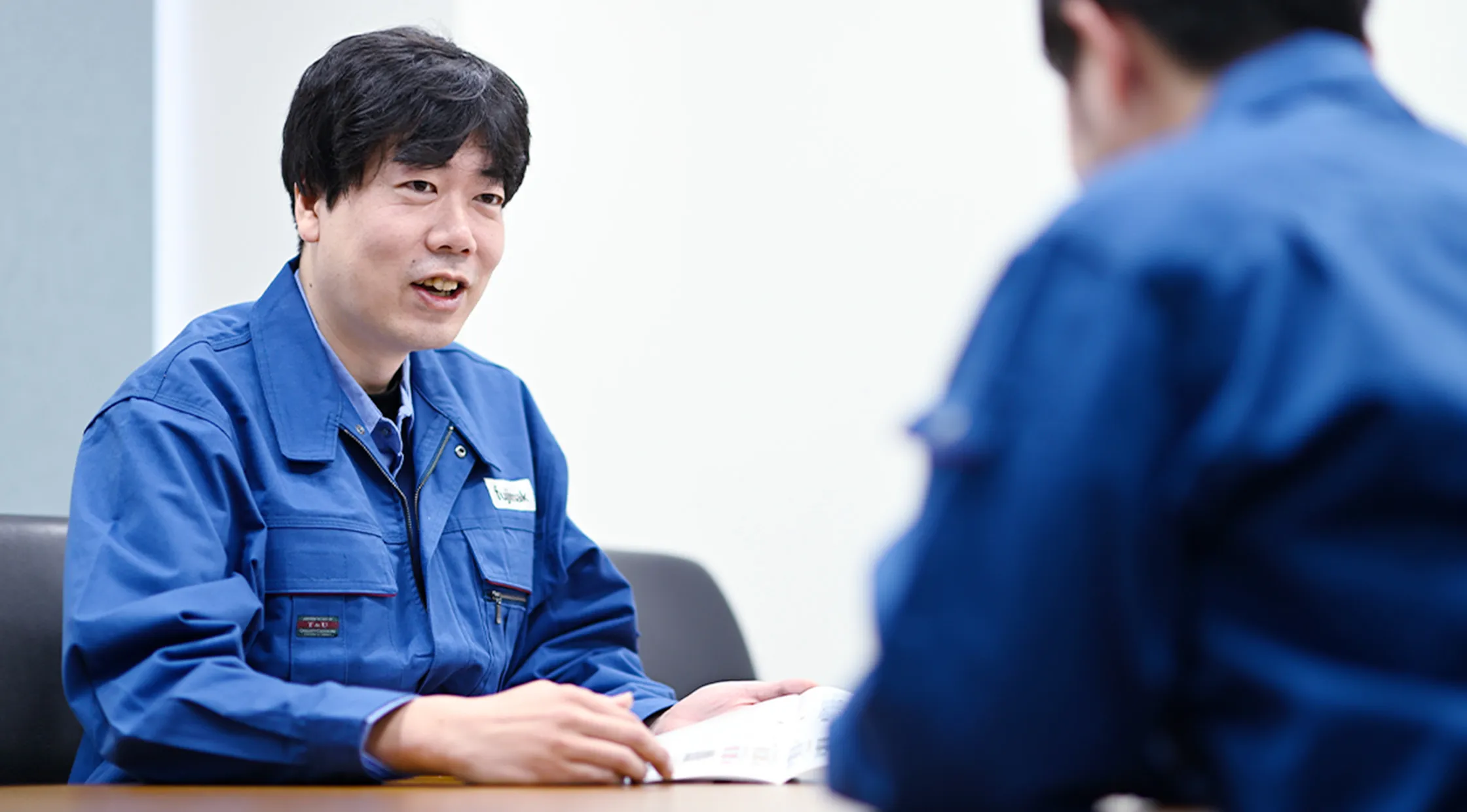 fujimakで働くサービスエンジニア職のKさんが同僚社員と打ち合わせをする様子